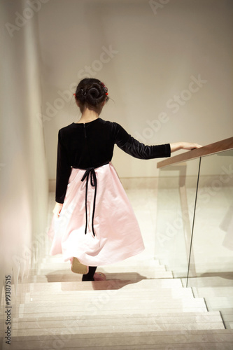 Young Girl Walking Down Staircase Wearing A Party Dress