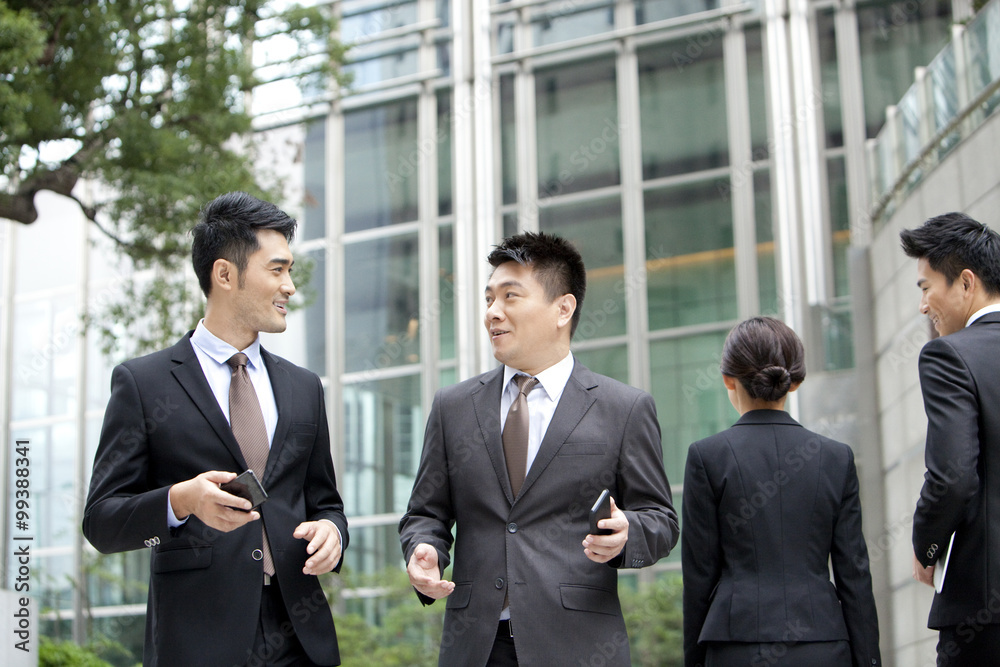 Happy office workers walking and talking with smart phones in hand outdoors, Hong Kong Happy office workers walking and talking with smart phones in hand outdoors, Hong Kong