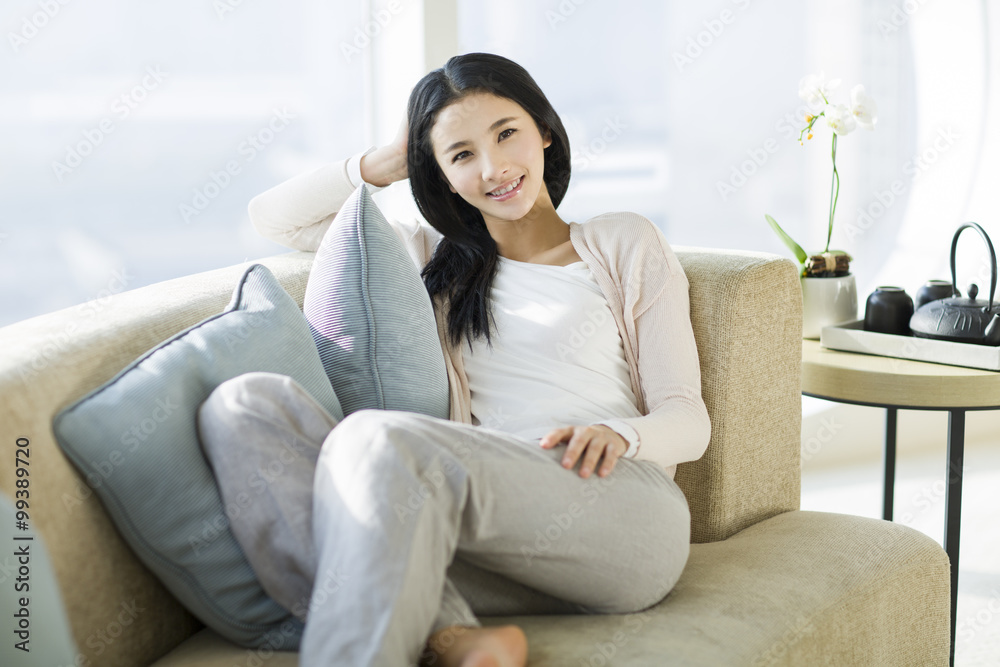 Happy young woman sitting on sofa Happy young woman sitting on sofa