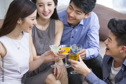 Happy young friends drinking cocktail in living room