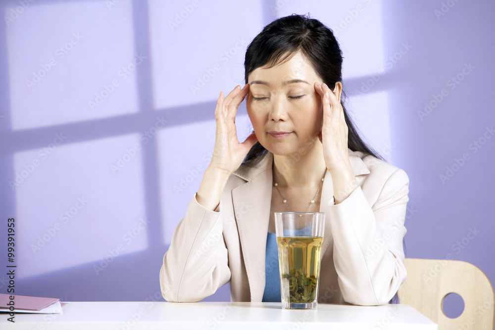 Woman Sitting At Table With A Drink And Looking Tired
