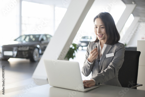 Car saleswoman working with laptop
