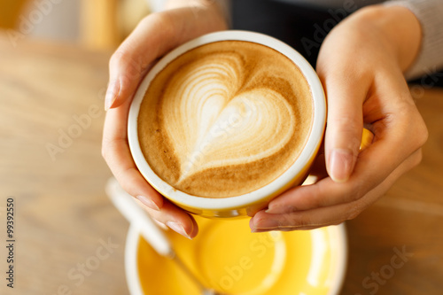 lady's hands holding cup with sth heart-shaped