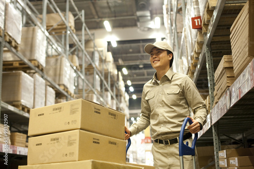 Male Chinese warehouse worker pushing boxes
