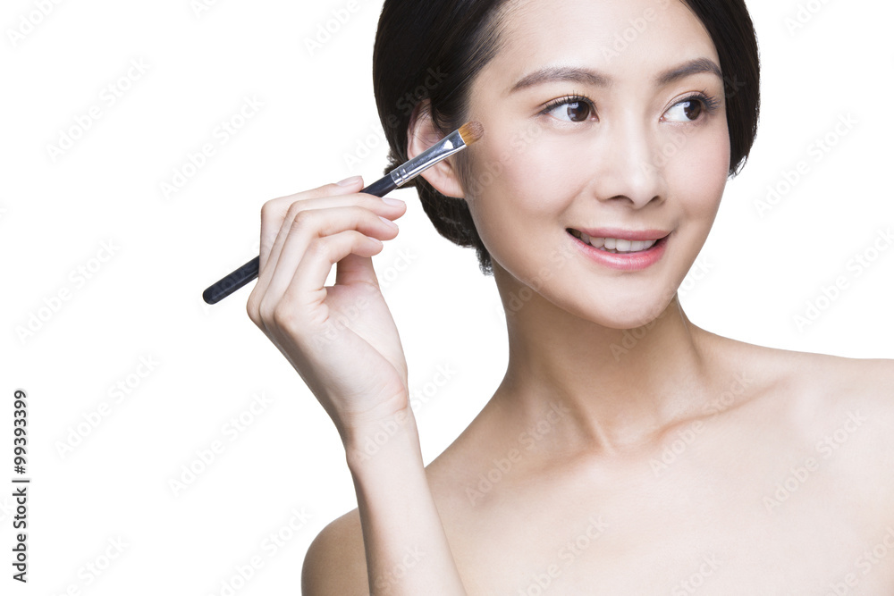 Beautiful young woman putting on make-up