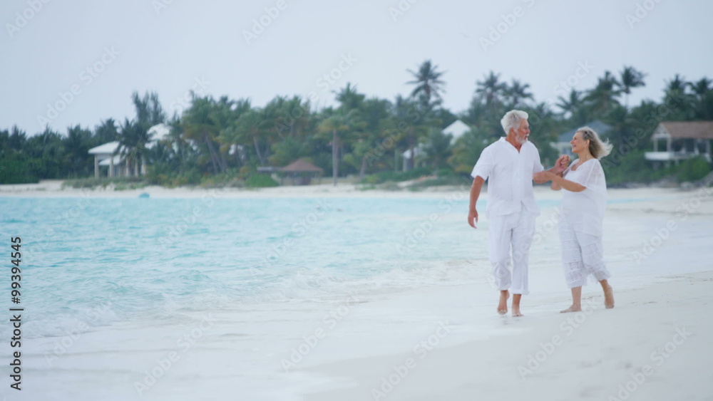 Mature Caucasian couple walking outdoors together on tropical beach Mature Caucasian couple walking outdoors together on tropical beach