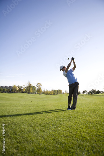 Man swinging golf club on golf course
