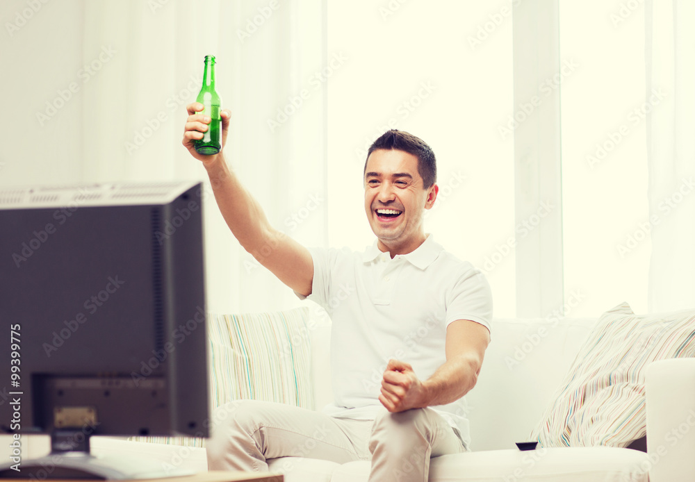 smiling man watching tv and drinking beer at home smiling man watching tv and drinking beer at home