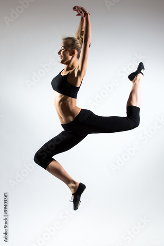 Young woman doing gymnastic exercise on white isolated background. Gimnastic jump of elegant nice blonde young girl.