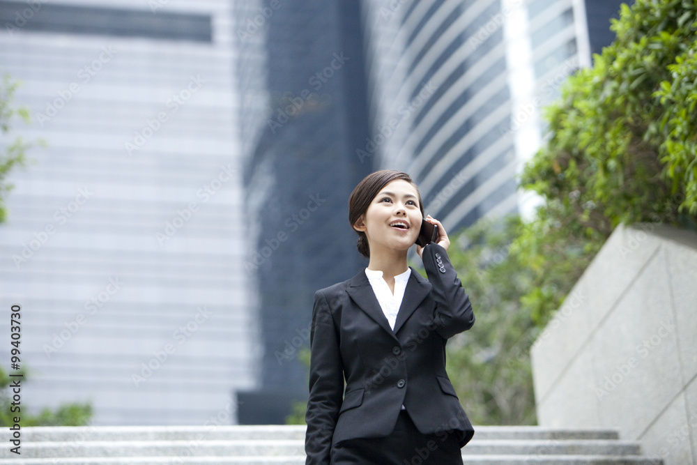 Happy businesswoman walking and talking on the phone outdoors, Hong Kong Happy businesswoman walking and talking on the phone outdoors, Hong Kong