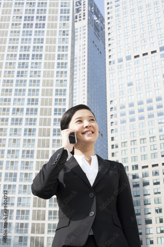 Happy young businesswoman on the phone in front of tall building Happy young businesswoman on the phone in front of tall building