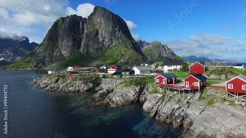 Aerial footage of scenic fishing village Hamnoya in Norway with its typical red houses, popular tourist destination on beautiful Lofoten islands on sunny summer day. Aerial 4k Ultra HD.