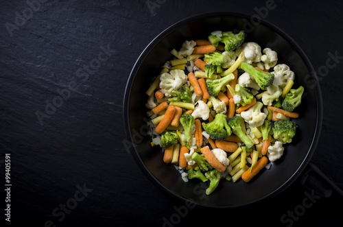 Frozen vegetables in black frying pan
