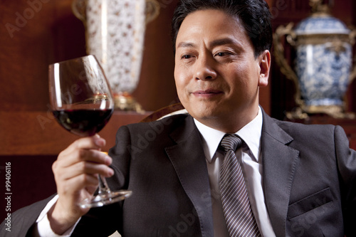 Fotografi Mature businessman enjoying wine in a luxurious room