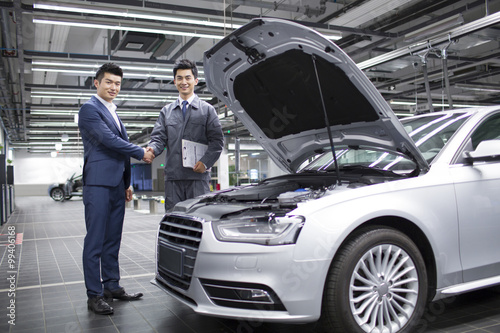 Auto mechanic and car owner shaking hands