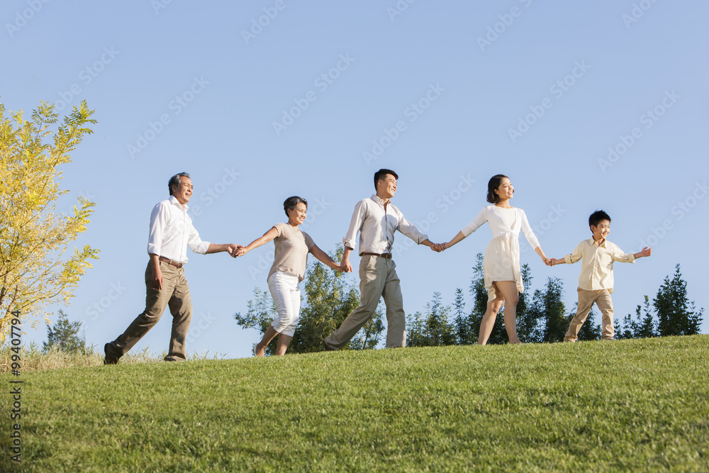 Big family holding hands one after another in a park Big family holding hands one after another in a park