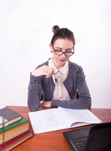 Young beautiful female teacher sitting at a table and reads the book