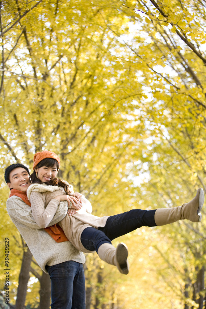 Young Man Playfully Picking Up His Girlfriend Young Man Playfully Picking Up His Girlfriend