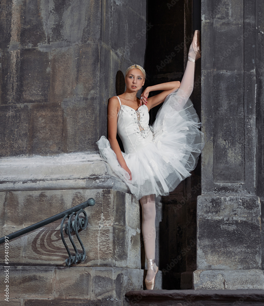 Fototapeta premium Reaching for dreams. Portrait of a beautiful female ballerina posing near an old castle with her leg raised up against the wall soft focus