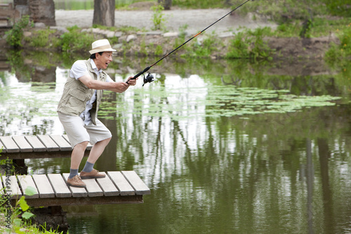 Old man fishing by a pond