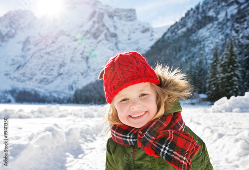 Smiling child standing in the front of snowy mountains