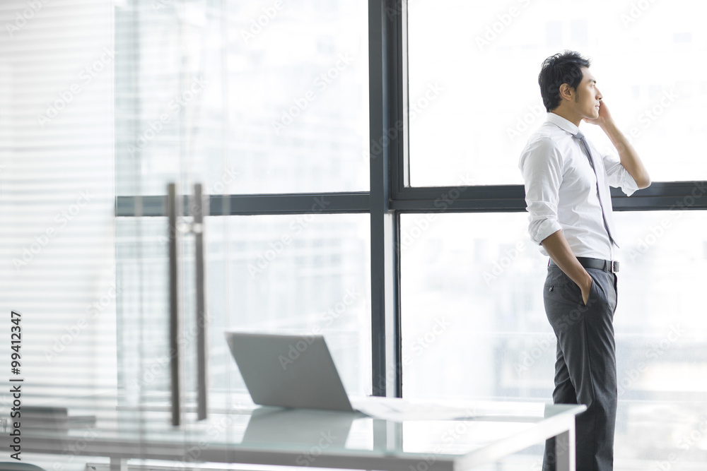 Young businessman talking on cell phone in office Young businessman talking on cell phone in office