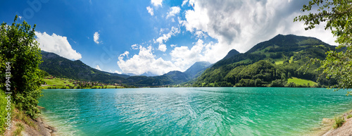 Fototapeta Naklejka Na Ścianę i Meble -  Panoramic image from the shore of a Green and Blue Mountain lake in the Swiss Alps