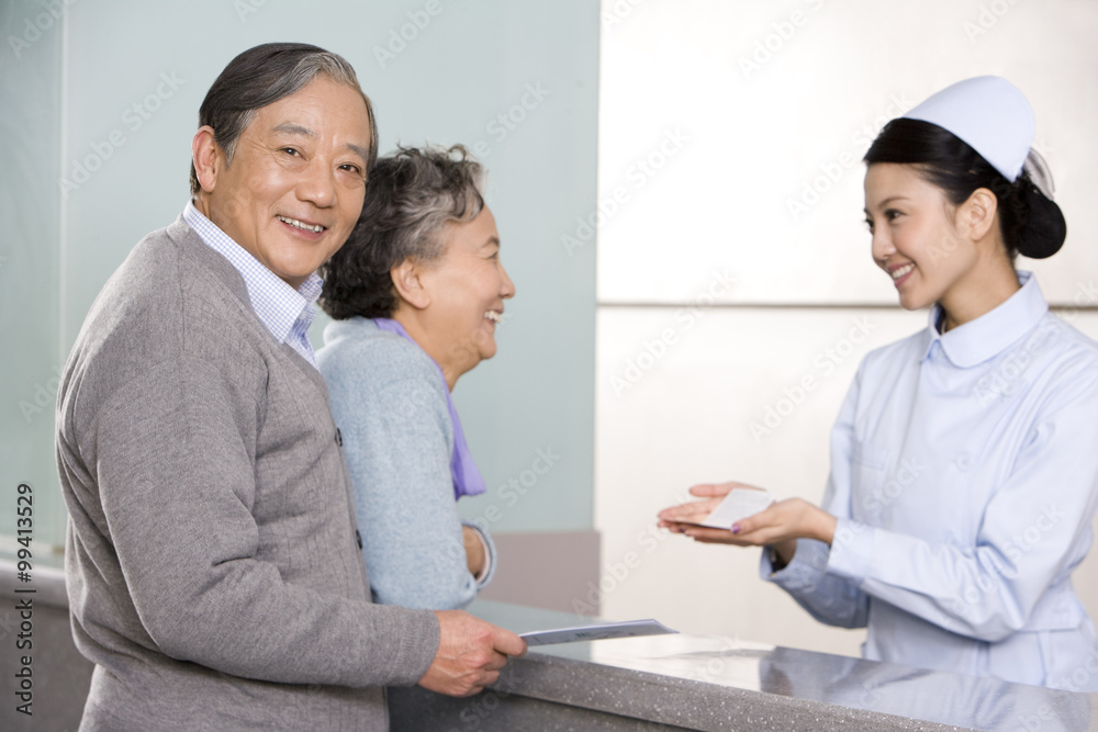 Young Nurse Helping Senior Couple at Nurses' Station Young Nurse Helping Senior Couple at Nurses' Station