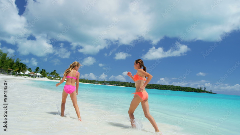 Young Caucasian sisters in swimwear on a luxury island beach Young Caucasian sisters in swimwear on a luxury island beach