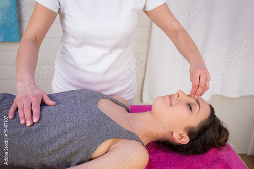 Happy woman having a reiki treatment in therapy room
