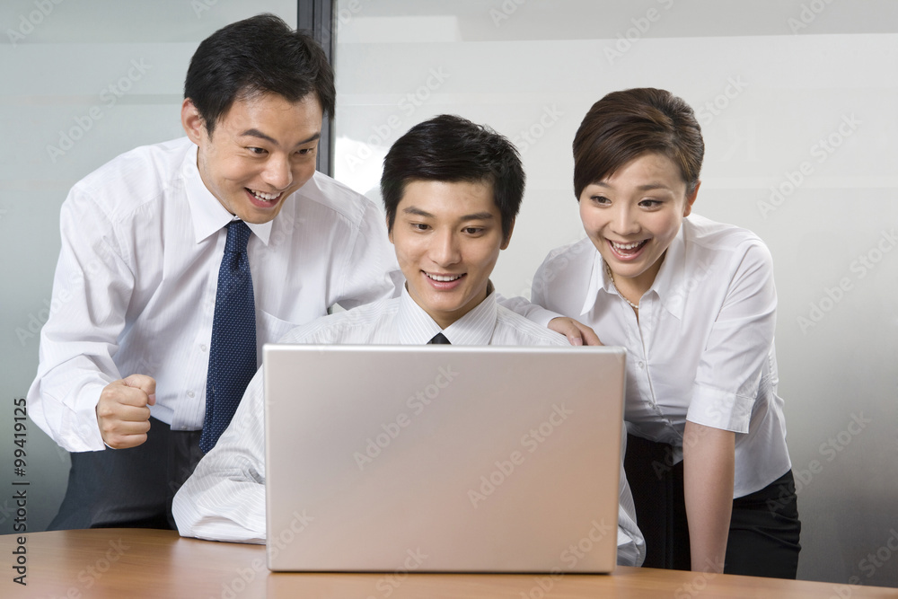 Young businessmen and businesswoman using laptop in office