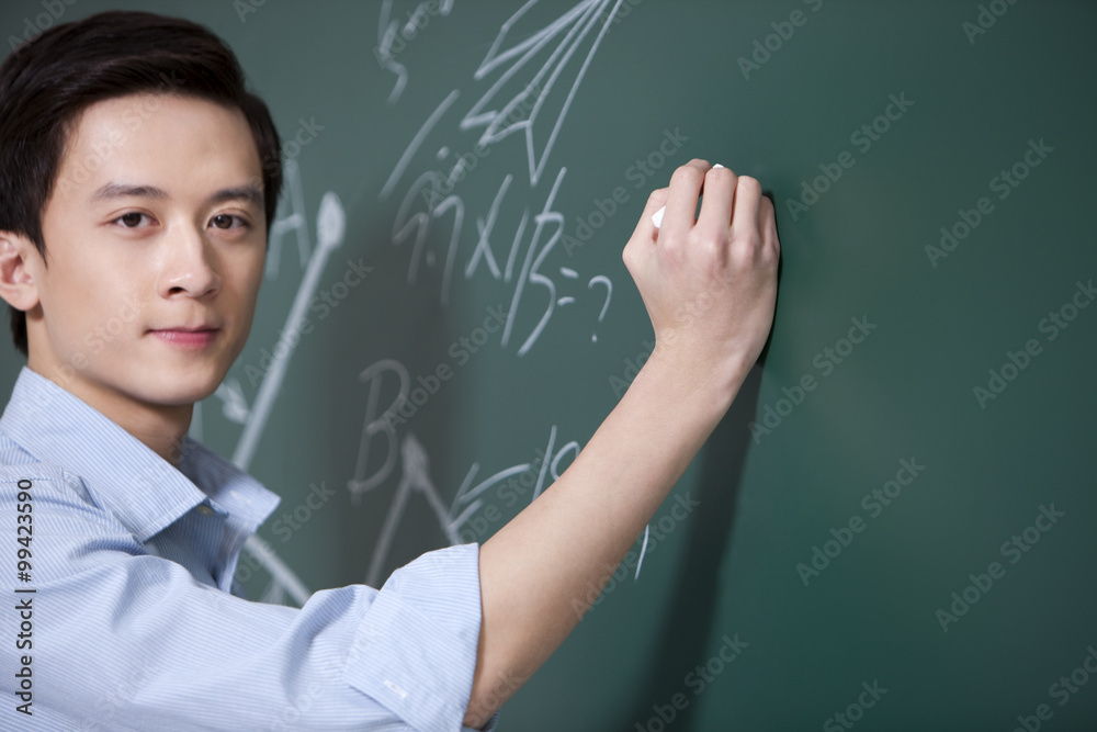 Professional male teacher writing on blackboard Professional male teacher writing on blackboard