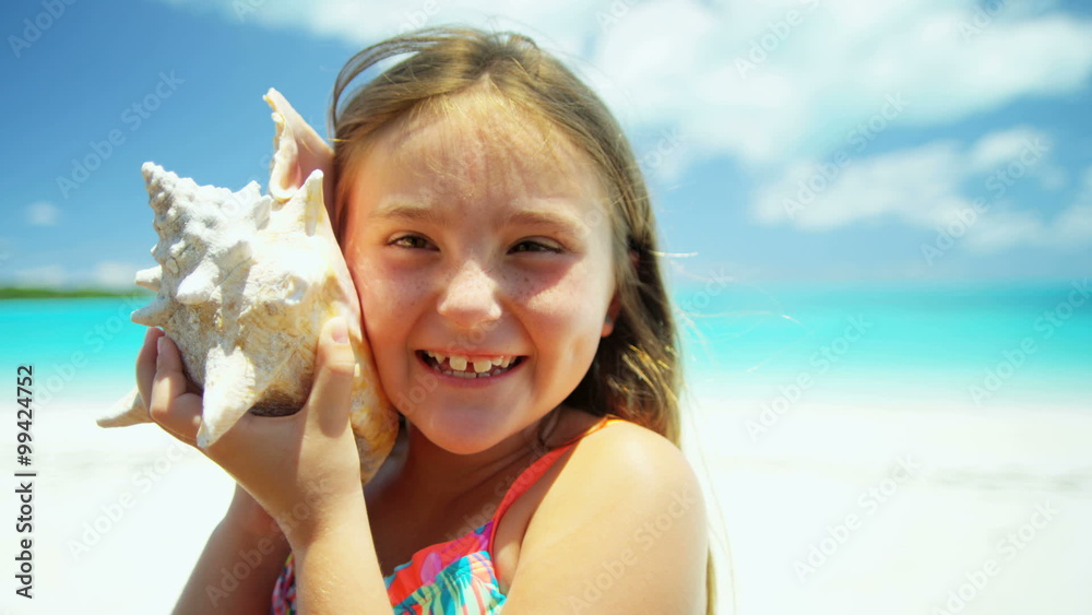 Portrait of a cute female Caucasian child on a beach with a conch shell