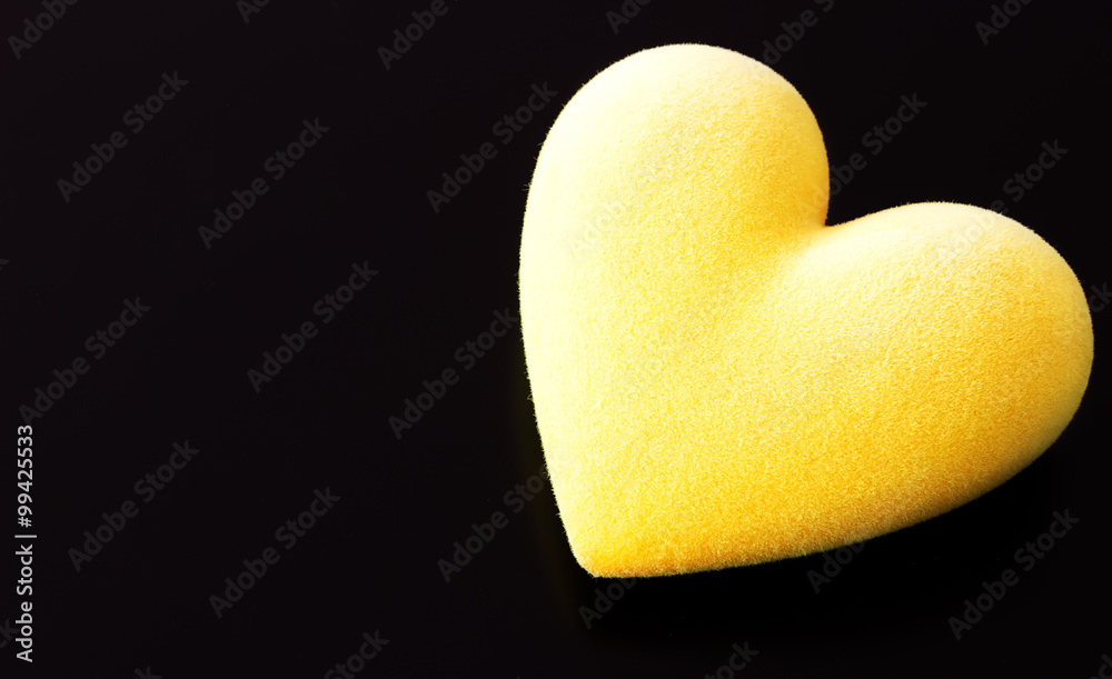 Fototapeta premium Yellow fluffy heart on a black background with a place for the text