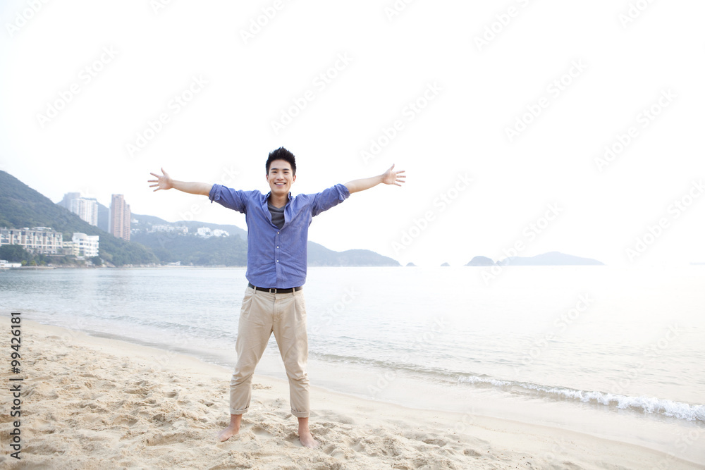 Cheerful young man arms outstretched on the beach of Repulse Bay, Hong Kong