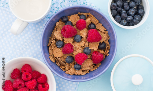 A healthy breakfast bowlful of cereals, raspberries and blueberries.  Looking down onto the table from above. photo