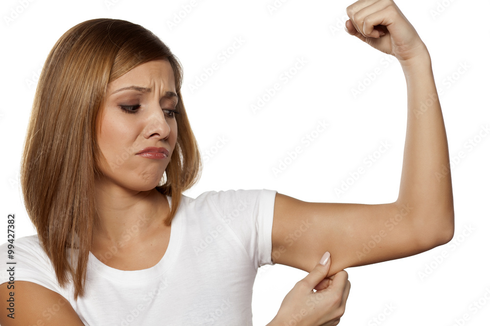 unhappy young woman pinchng the skin on her arm unhappy young woman pinchng the skin on her arm