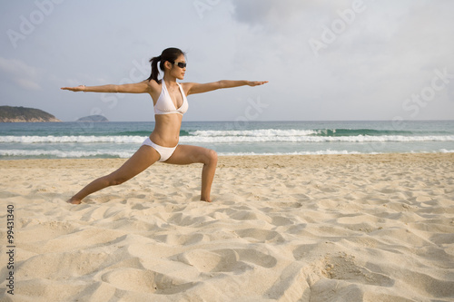 Young woman doing yoga on the beach