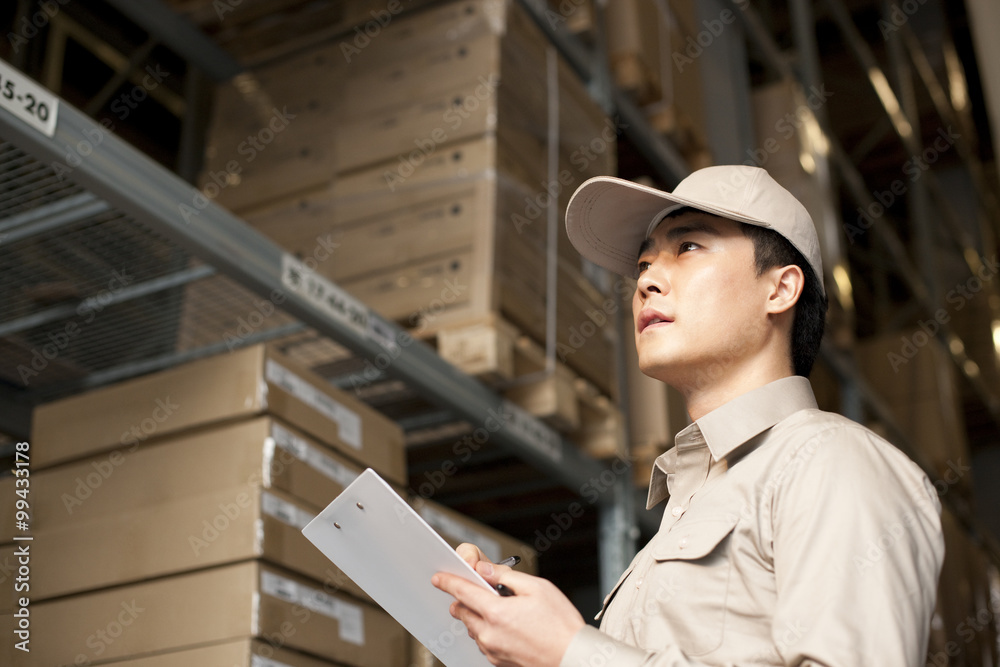 Male Chinese warehouse worker with clipboard Male Chinese warehouse worker with clipboard