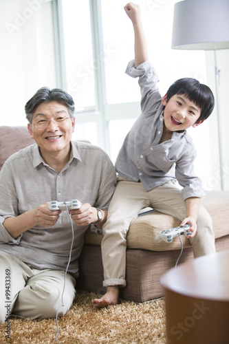 Cheerful grandfather and grandson playing video game © Blue Jean Images