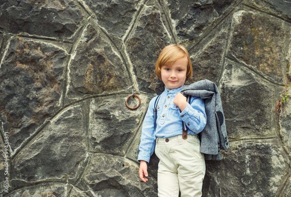 Vintage fashion portrait of a cute little blond kid boy, young boy posing outdoors