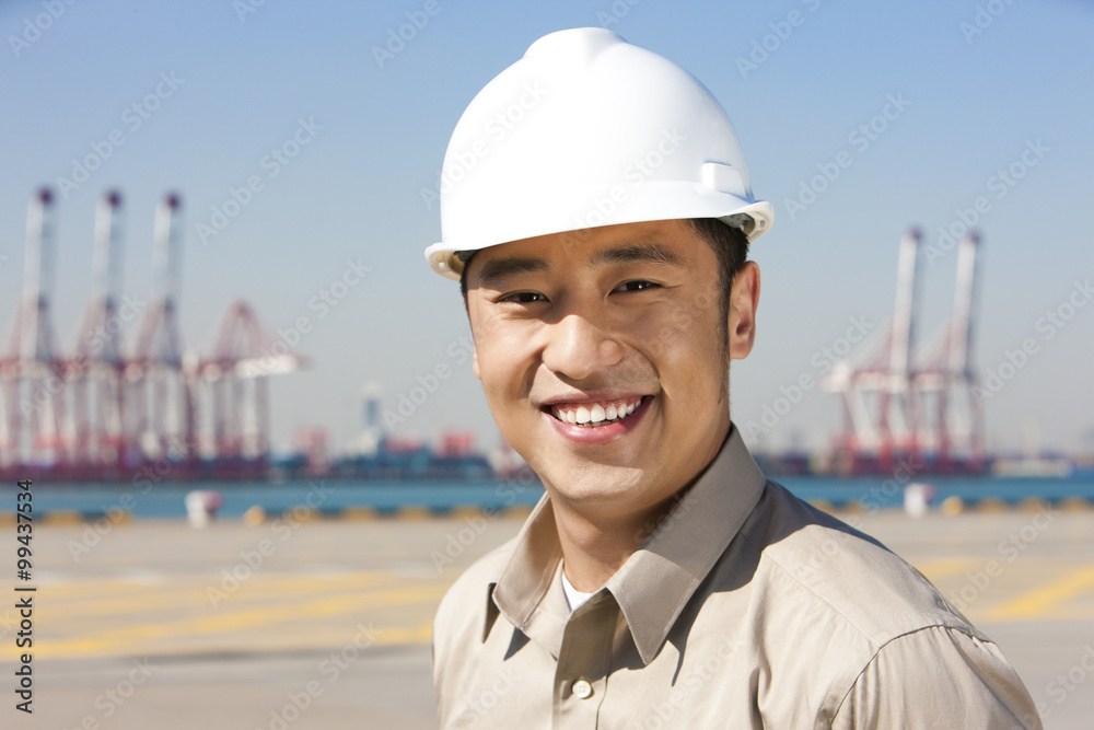 Male shipping industry worker in a shipping dock smiling Male shipping industry worker in a shipping dock smiling
