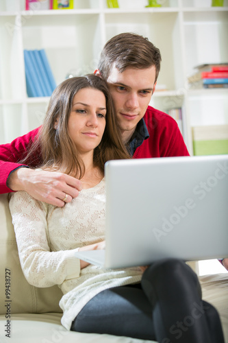 Young couple relaxing on sofa with laptop in the living room.Selective focus