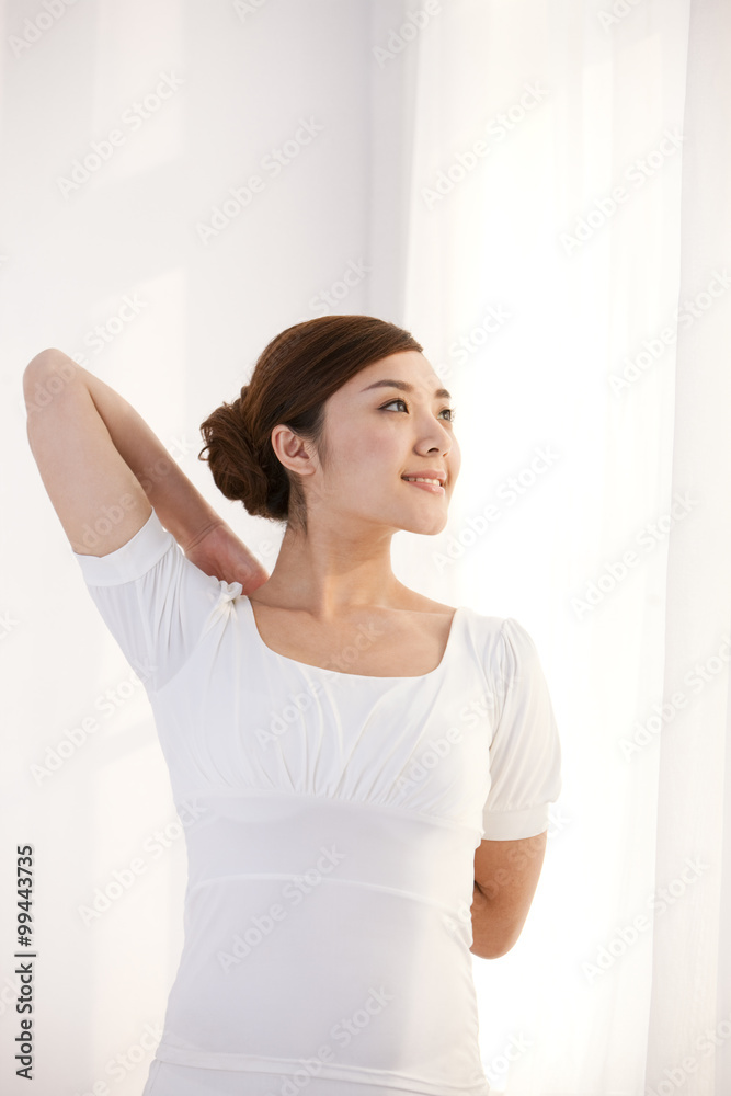 Young woman stretching and looking calm by the window Young woman stretching and looking calm by the window