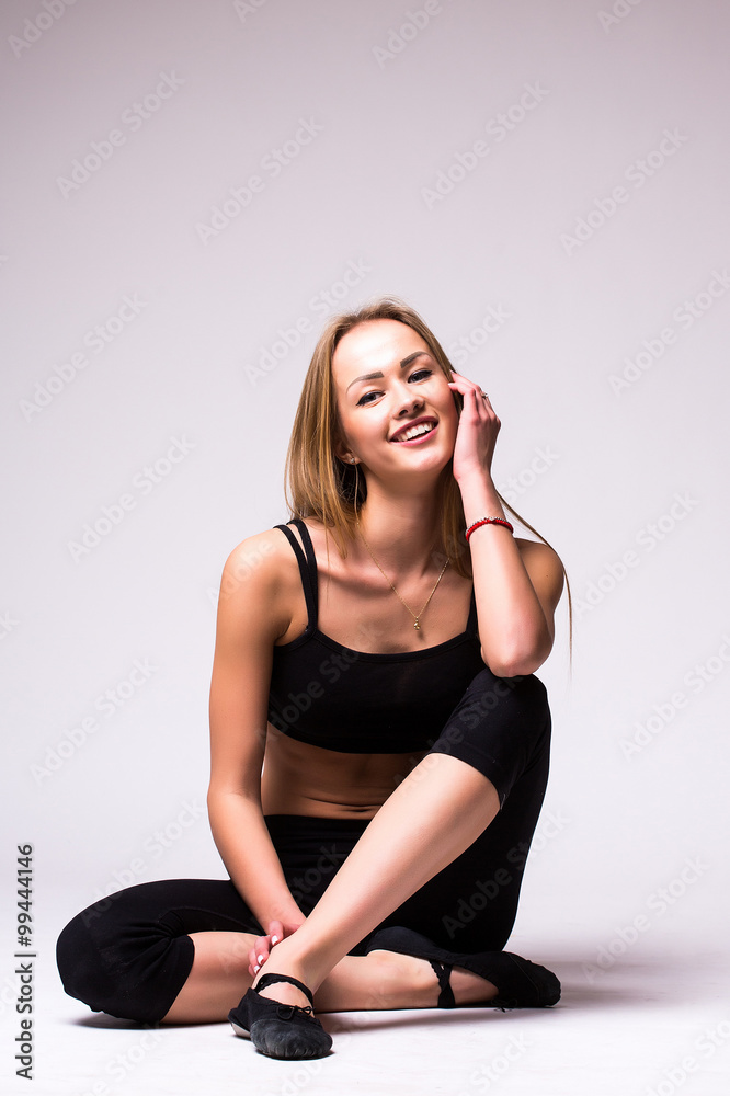 Nice Young woman doing gymnastic exercise with crossed legs on grey isolated background Nice Young woman doing gymnastic exercise with crossed legs on grey isolated background