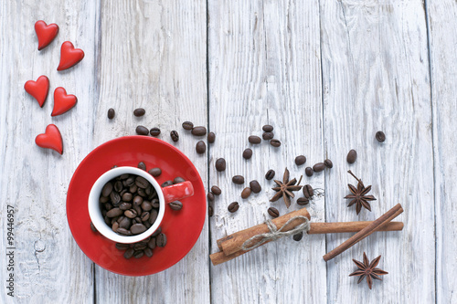Red cup with coffee beans and red hearts on wooden background 