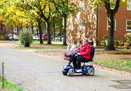 Seniorin mit Elektromobil wendet auf der Straße und lächelt 