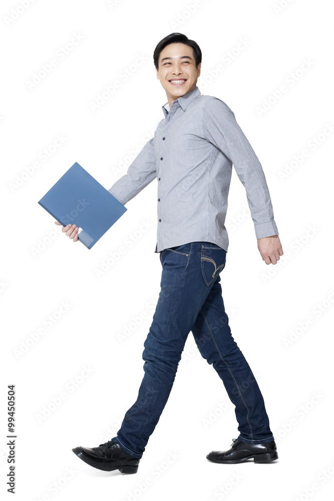 A young man walking with a folder in hand A young man walking with a folder in hand