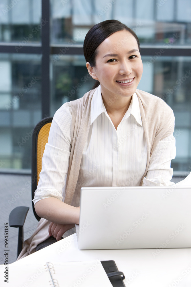 Businesswoman sitting with a laptop and a notebook Businesswoman sitting with a laptop and a notebook