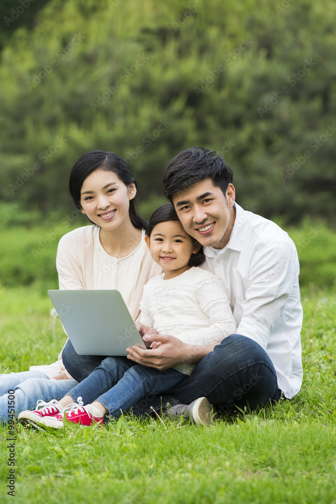 Happy family using laptop on the grass Happy family using laptop on the grass